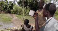 A woman and two kids drinking water from a river in Kenya